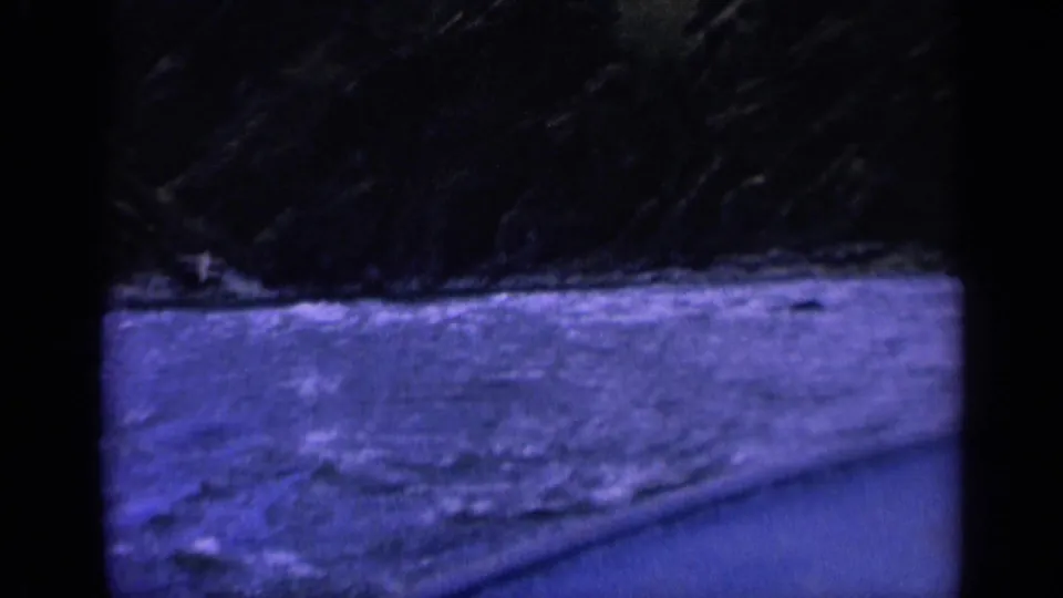 1963 Washington 8mm frame showing turbulent water near a dark shoreline from a moving boat viewpoint.
