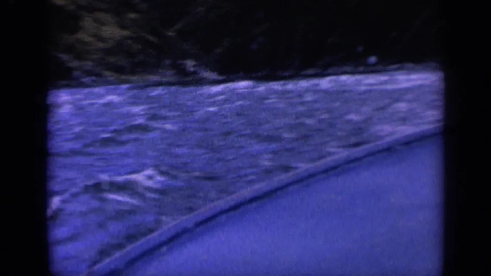 1963 Washington home-movie frame of rough water along a boat side, with dark shore or bank beyond.