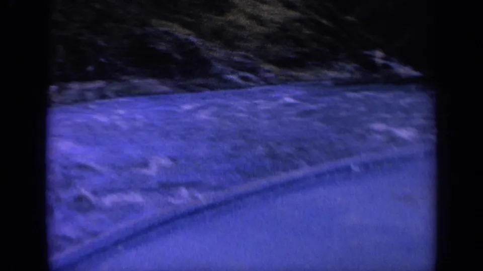 1963 Washington 8mm frame with motion-blurred blue water, a small boat edge, and shadowed riverbank in low light.