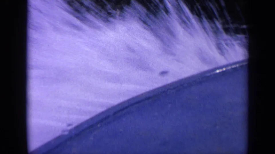 1963 Washington home-movie frame showing bright foamy wake rising beside the curved edge of a moving boat.