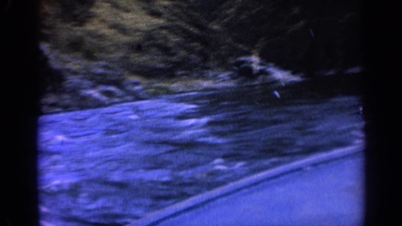 Blue-tinted river surface beside a steep rocky shoreline.