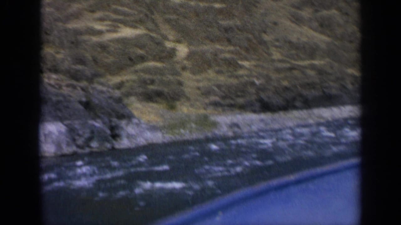 The boat passes close to choppy water and a rugged Washington shoreline in a soft 8mm home-movie frame.