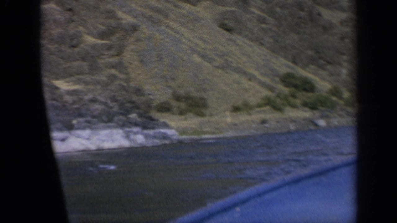 River and hillside shoreline framed by the boat edge and film borders.