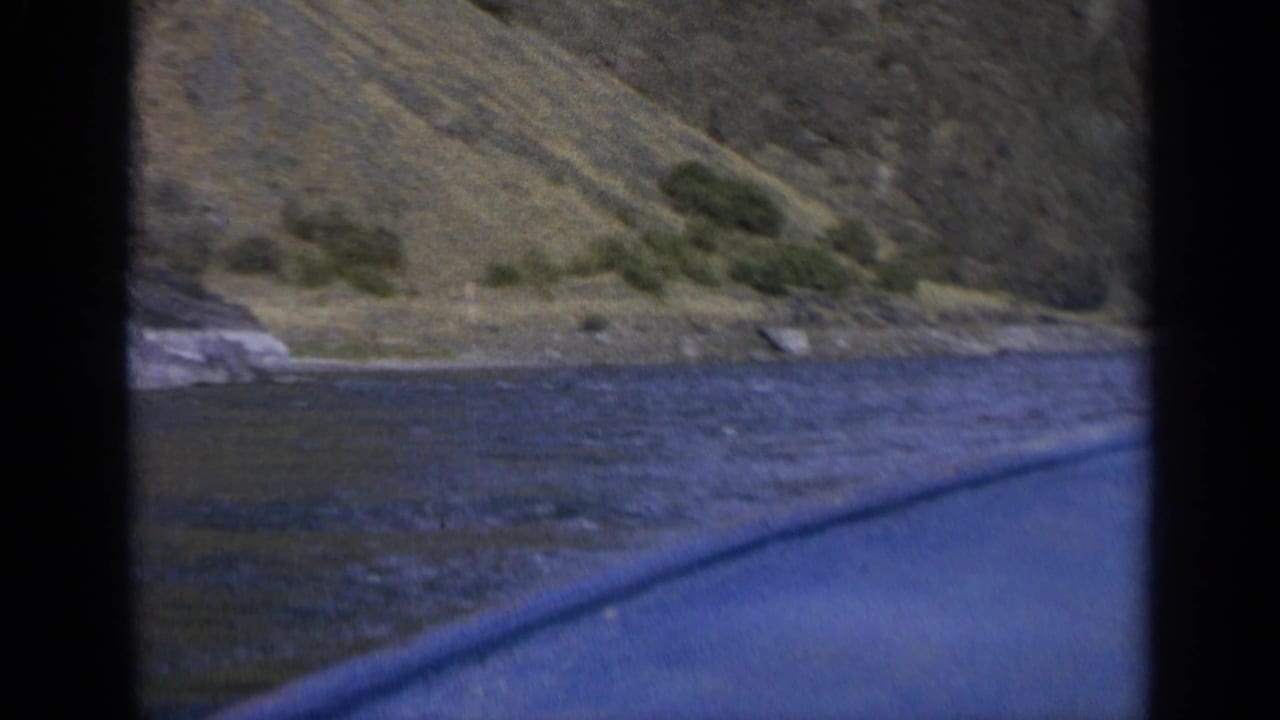 Lake surface and sloped shoreline seen between dark boat framing.