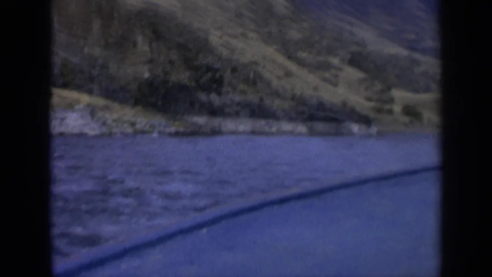 1963 Washington 8mm frame showing a blue river beside dry rolling hills, seen through dark film-frame borders.