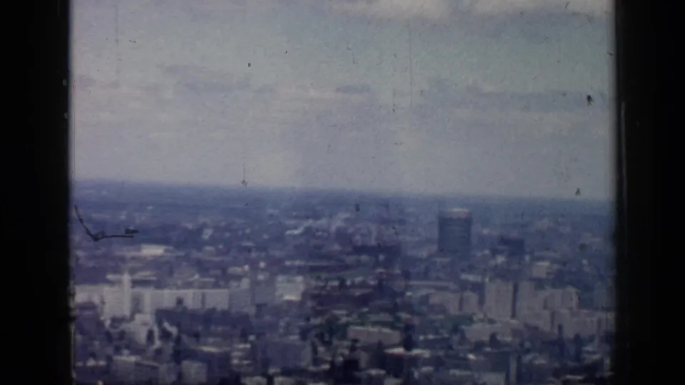 1957 8mm home-movie frame showing a hazy elevated view across Chicago buildings and distant high-rises.