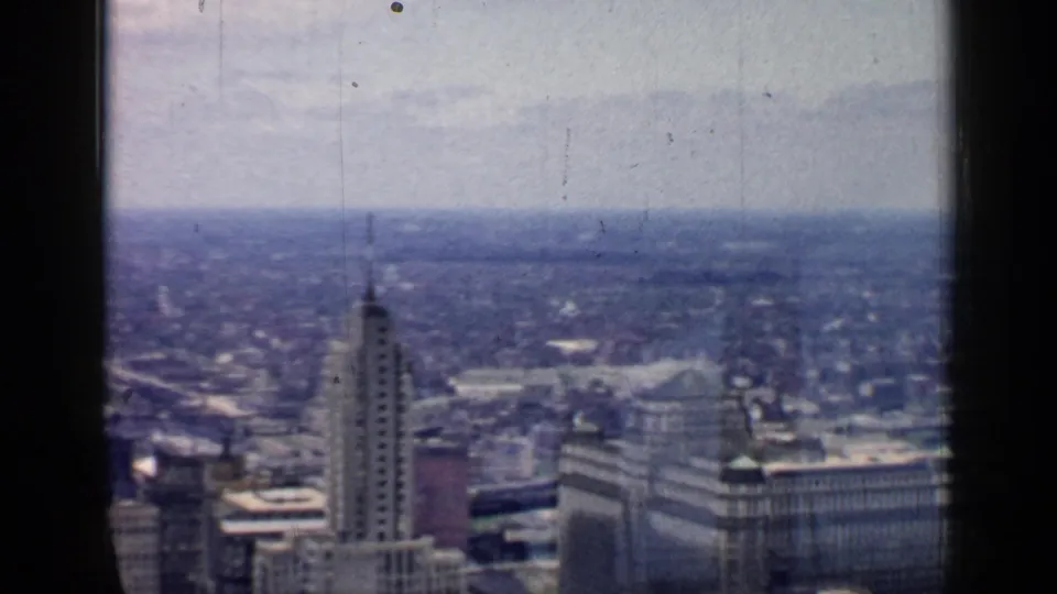 1957 Chicago cityscape with a prominent downtown tower and surrounding mid-century buildings seen through dark window framing.