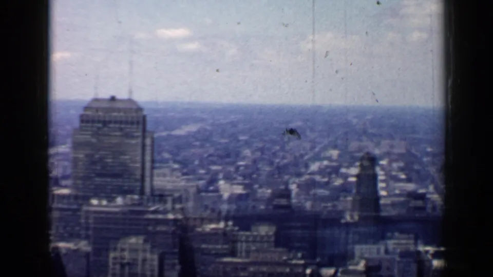 Chicago city view with a prominent rectangular tower, surrounding mid-century buildings, broad urban grid, and visible 8mm scratches.