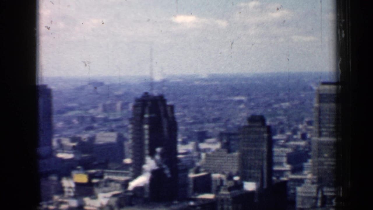 Elevated view of Chicago skyscrapers and distant city horizon through dark window edges.