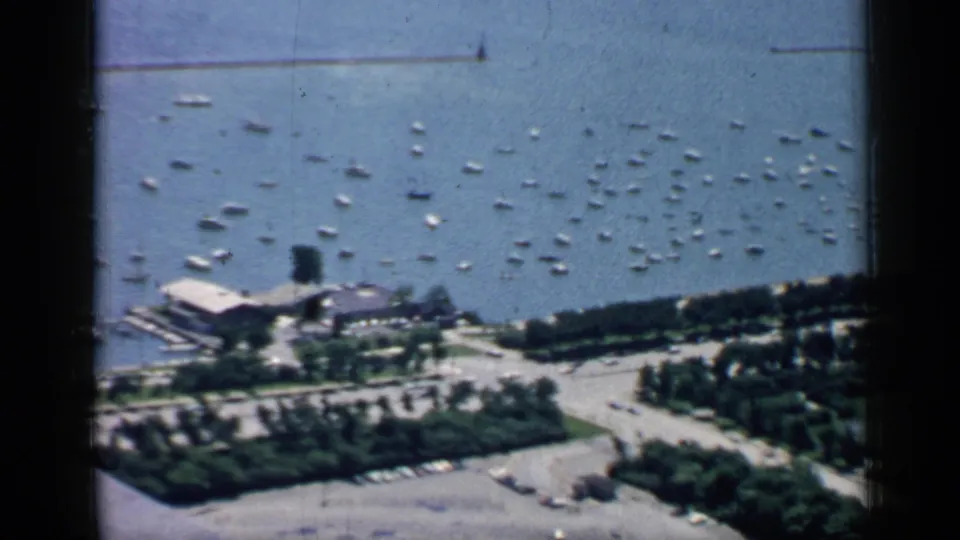 1957 Chicago lakefront view showing many small boats, a marina structure, shoreline roads, and planted parkland.