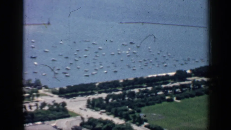 1957 Chicago lakefront from above, with boats offshore, a tree-lined boulevard, paths, and a broad green field.