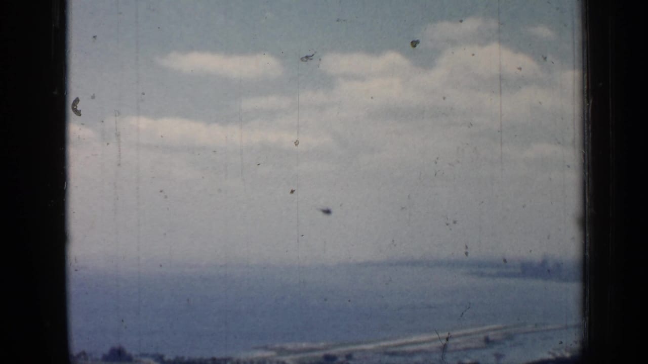 Elevated view of water and distant shoreline framed by dark window edges.