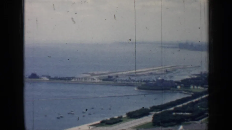 Elevated 1957 Chicago waterfront view showing small boats, a tree-lined shore road, open water, and a long pier or causeway.