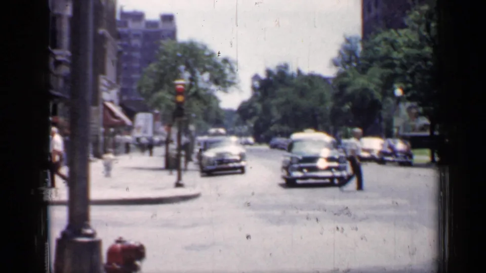 1957 Chicago street scene showing traffic, pedestrians, trees, streetlights, and a red fire hydrant along the curb.