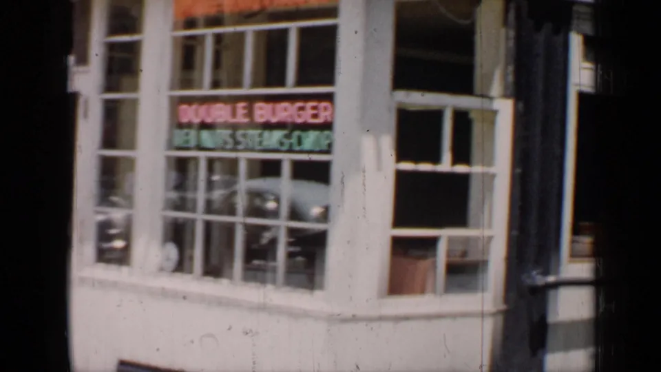1957 Chicago frame focused on the restaurant window, neon Double Burger lettering, and adjacent storefront details.