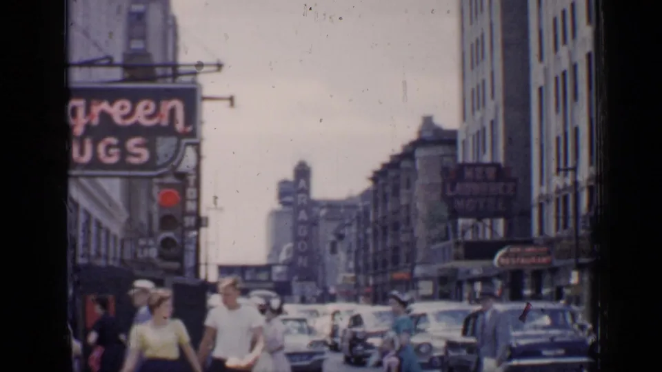 Chicago street scene from 1957 with people in summer clothing, mid-century cars, and visible drugstore and ballroom signage.
