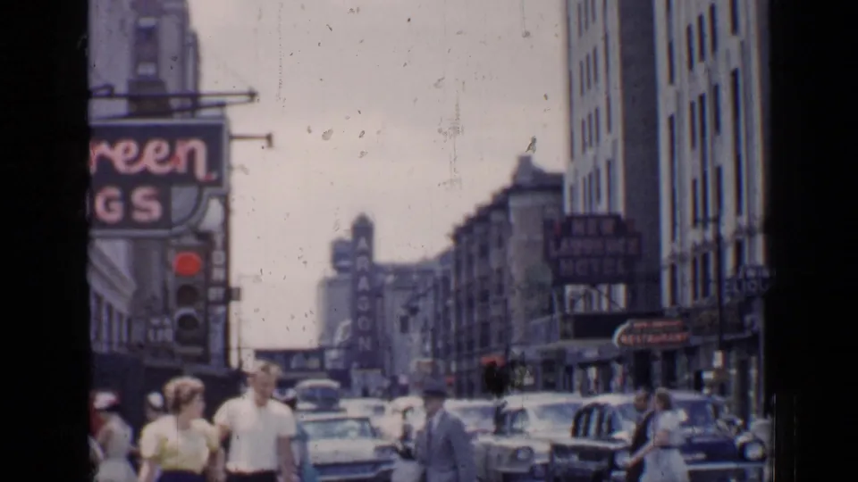 1957 Chicago view showing pedestrians near the curb, traffic, tall buildings, and signage for Aragon and nearby businesses.