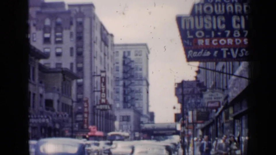 Chicago commercial block in 1957 with traffic, pedestrians, a hotel sign, and a large Howard music and records sign.