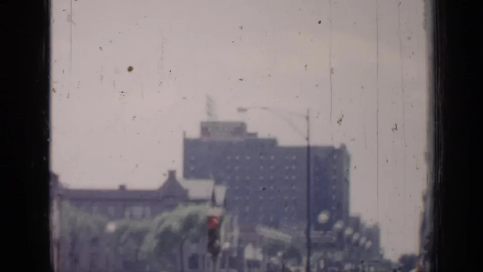 1957 Chicago frame with a soft-focus urban street, distant high-rise, traffic signal, streetlights, and visible film gate edge.