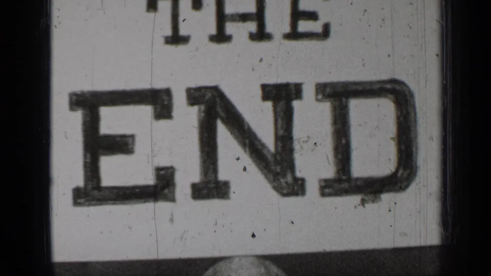 Close 8mm home-movie title card reading “THE END,” framed by dark film edges with visible dust and scratches.