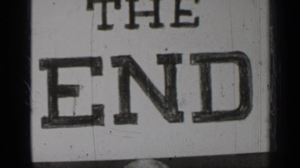 Final 8mm frame showing the “THE END” title card in close view, with soft focus, scratches, dust, and dark film borders.