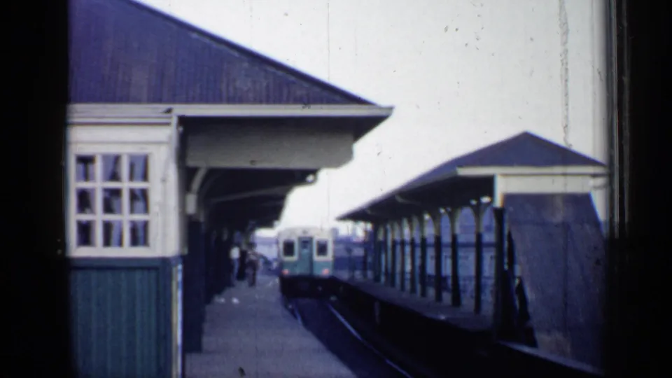 1958 Chicago station view with a covered platform, small shelter, and passenger train cars visible along adjacent tracks.