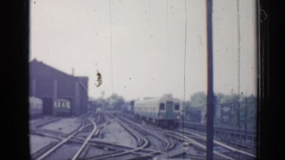 1958 Chicago 8mm view down a rail yard or station approach as a passenger train moves away through several switching tracks.