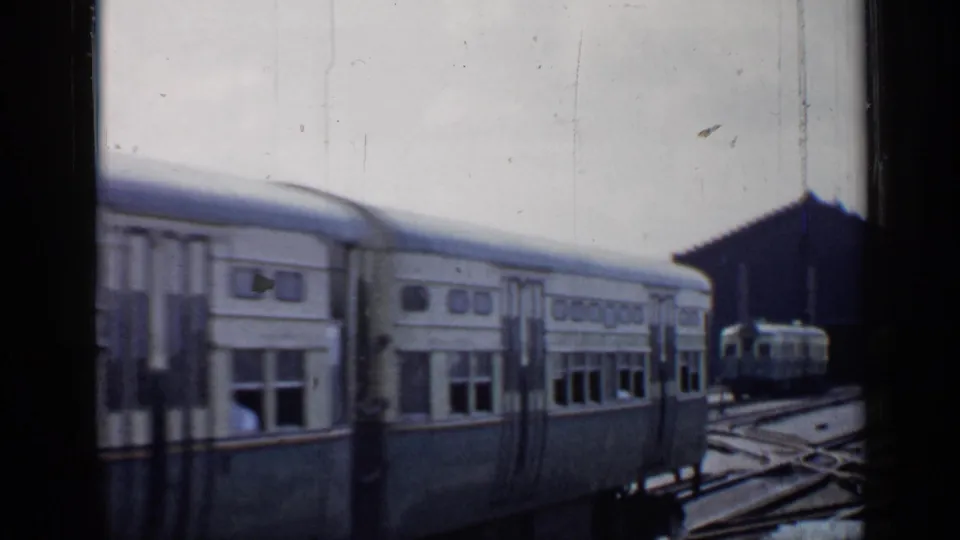 1958 Chicago 8mm frame showing commuter railcars near station tracks, with soft focus and visible film borders.