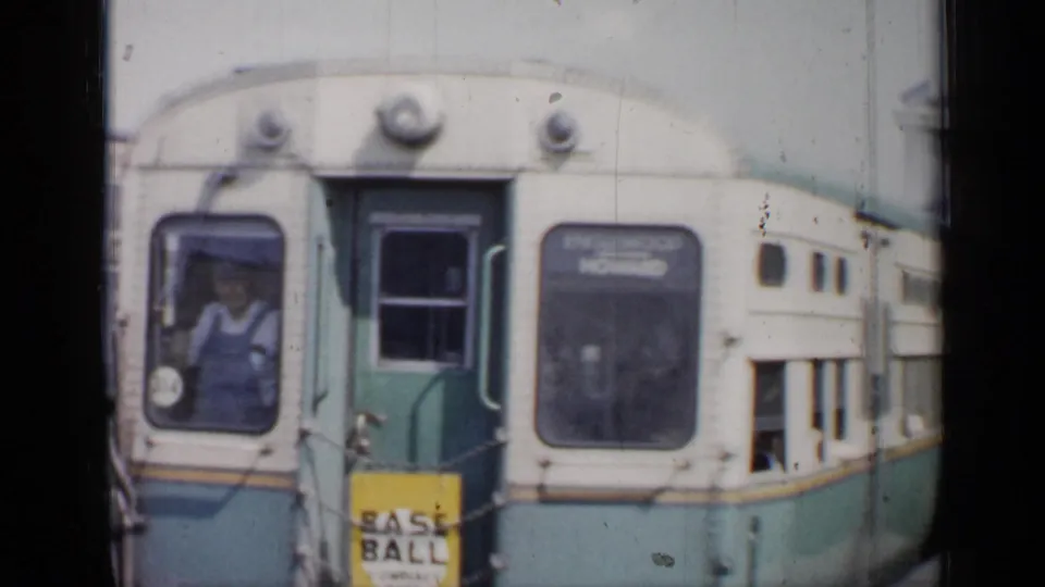 Close 8mm frame of the train front at the Chicago platform, showing cab windows, front sign panels, and a person inside the car.