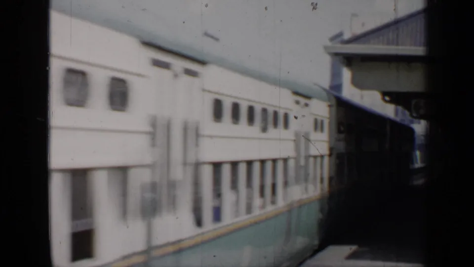 The train's side profile fills the frame as it passes a Chicago station platform, with windows and canopy structure visible.