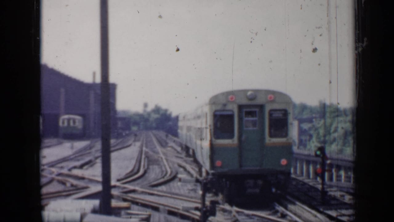 Rail car farther along multiple tracks beside posts and a dark building.