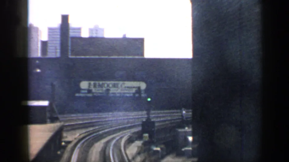 1958 Chicago train view of curving tracks, a green signal light, industrial walls, and the E. & M. Moore sign.