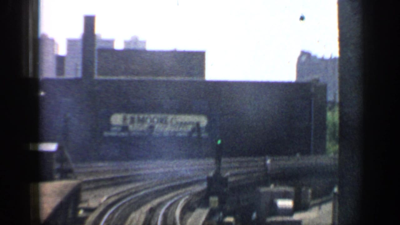 Curving rail tracks pass an industrial wall with a large E.R. Moore Company sign.