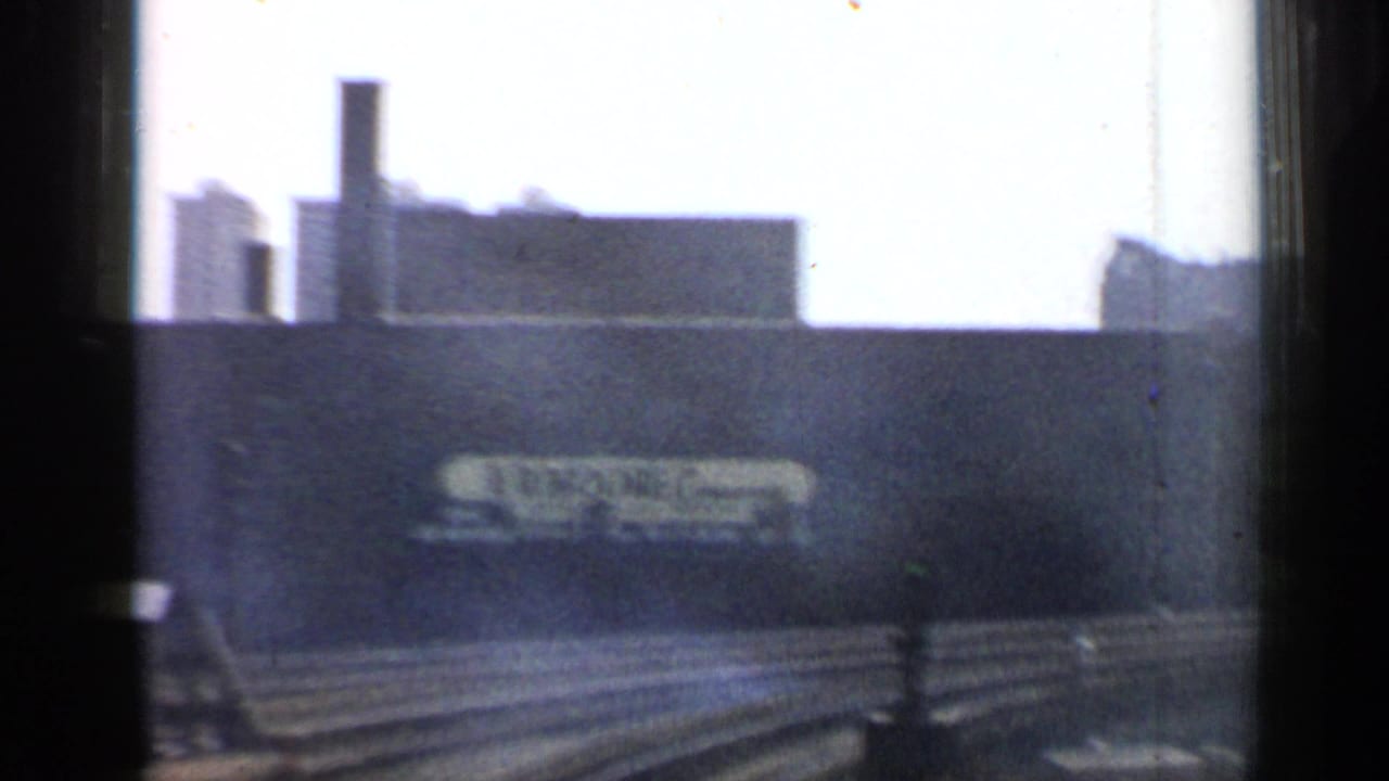 Industrial wall with E.R. Moore Company sign seen beyond rail tracks and dark frame edges.