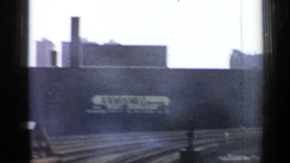 1958 Chicago rail approach with tracks in the foreground and the E.R. Moore Company sign on a dark industrial wall.