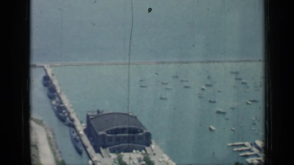 1958 Chicago waterfront view showing a pier or dock structure, a large terminal-like building, breakwater, and small boats scattered across the water.