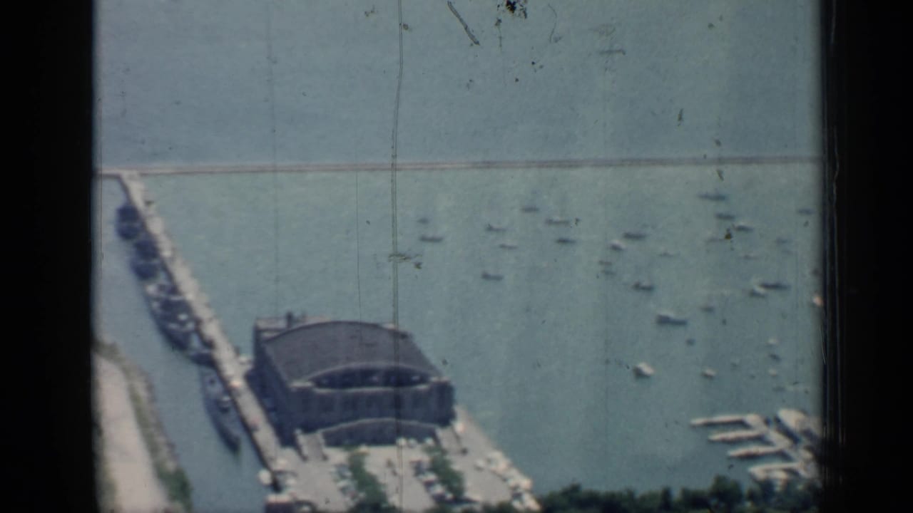 High-angle harbor view with boats, pier building, breakwater, and lake water.