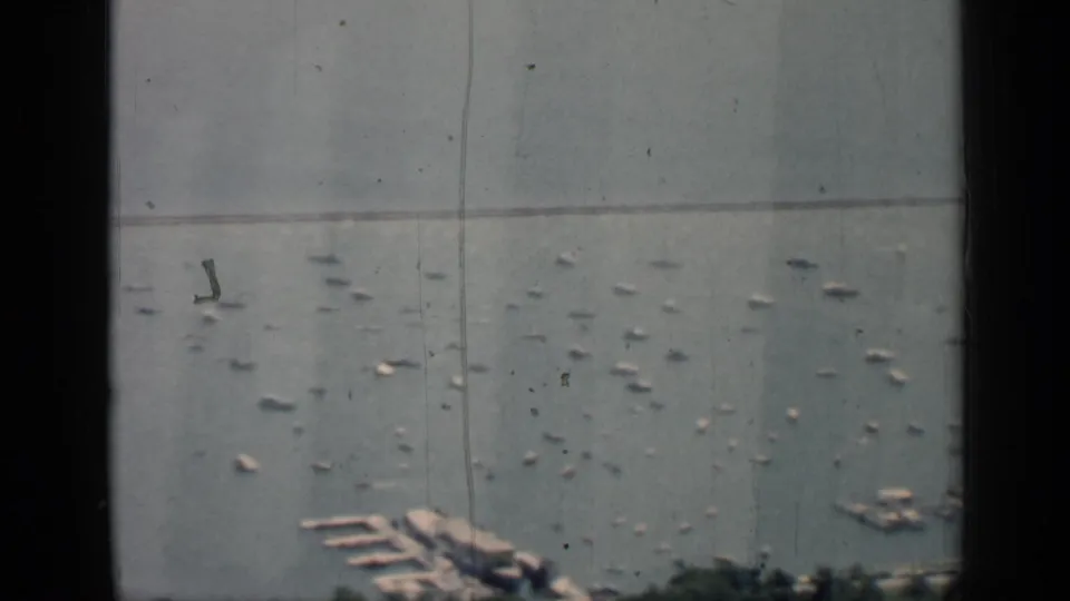 1958 Chicago harbor view from an elevated window, showing small boats on the water, piers, shoreline buildings, and a distant horizontal pier.