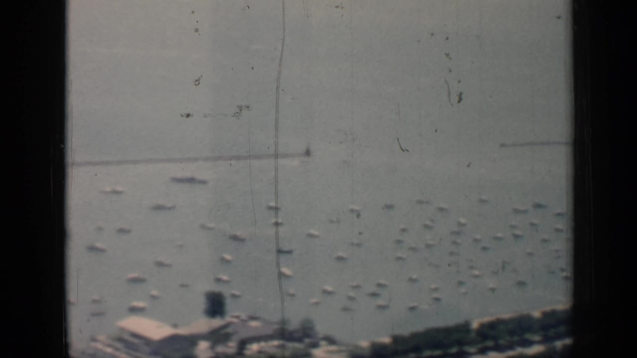 Harbor water filled with anchored boats, a shoreline edge, and a dark vertical window frame.