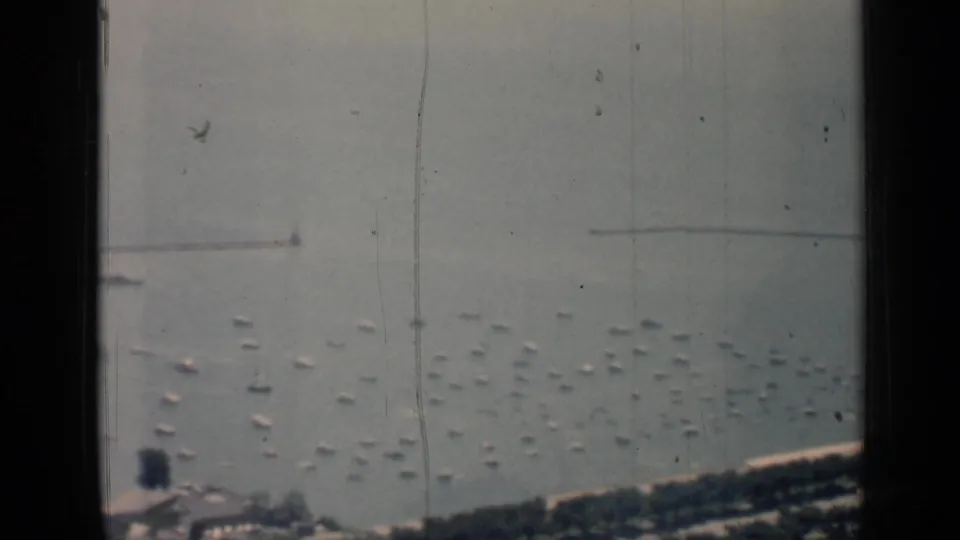 Soft 8mm frame of the 1958 Chicago harbor, with rows of small boats below a long pier or breakwater and shoreline structures at the bottom edge.