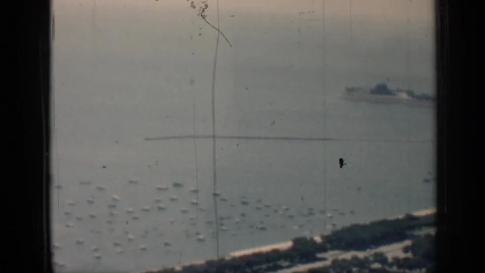 A high-angle 1958 Chicago lakefront view shows scattered small boats, a distant linear pier or breakwater, and shoreline at the bottom edge.