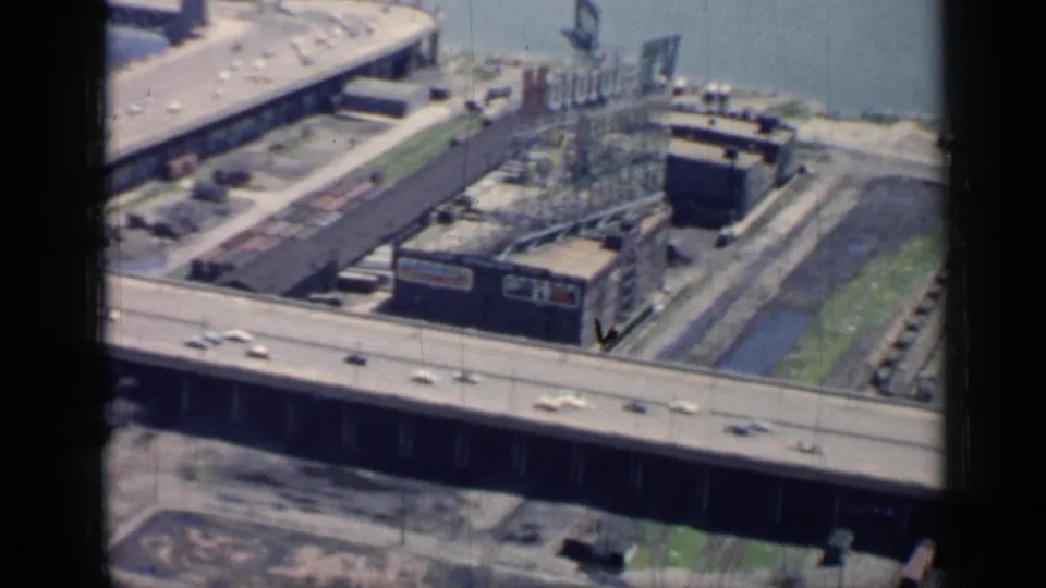 1958 Chicago frame with a curved elevated roadway, cars, river water, and industrial structures below.