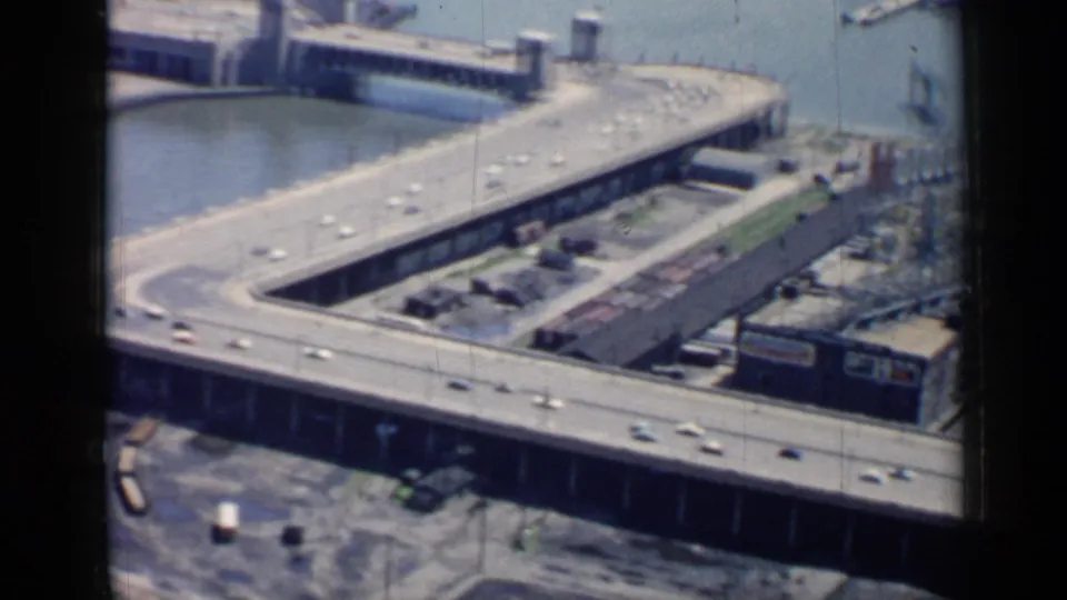 1958 Chicago 8mm still of elevated road decks and ramps crossing an industrial riverfront area.
