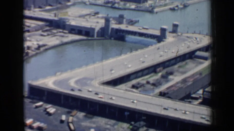 1958 Chicago frame showing a bridge curving over the river with cars and industrial structures in view.