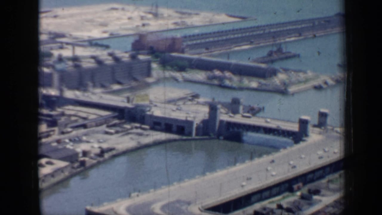 Aerial view of canal, industrial buildings, bridge structures, and lakefront piers.