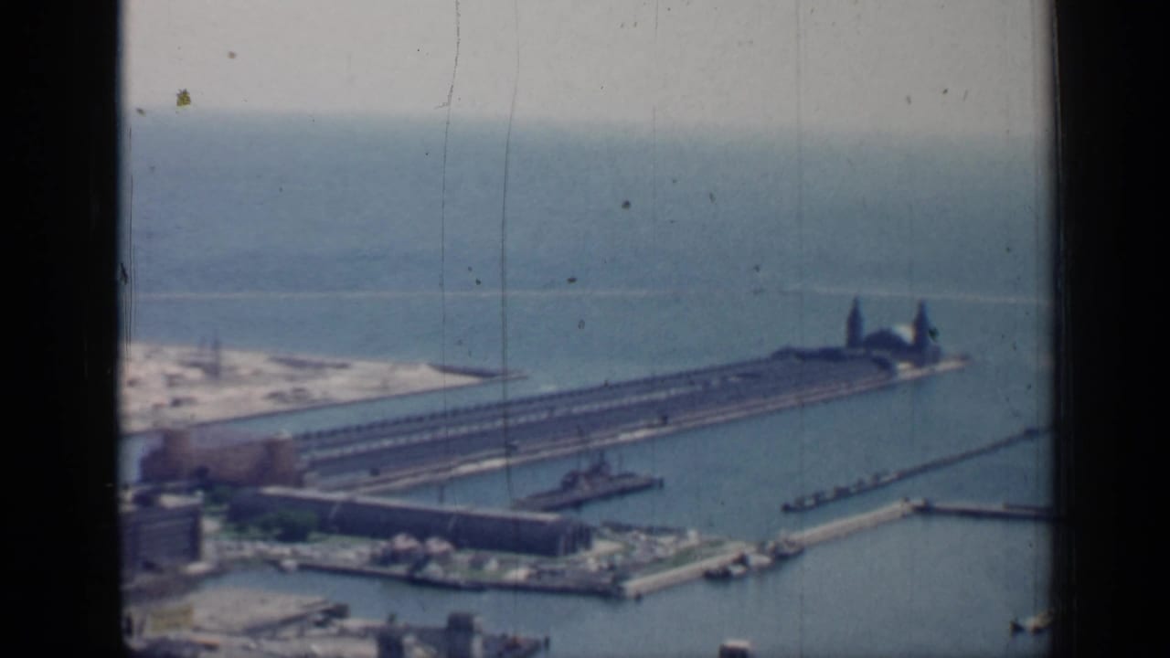 Aerial view of harbor piers, open water, small boats, shoreline structures, and window divider.