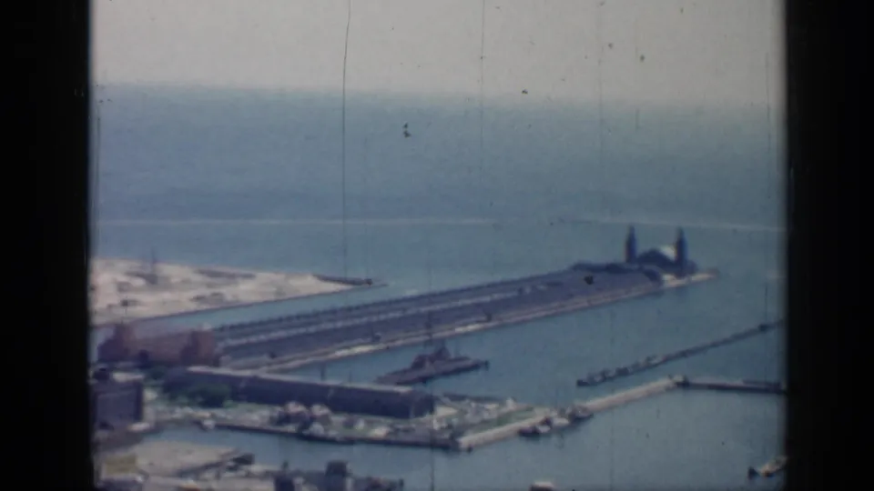 Chicago harbor from an elevated 1958 8mm view, showing a long pier, Lake Michigan, waterfront buildings, boats, and visible film wear.