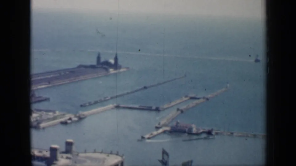Elevated 1958 Chicago harbor view with piers, breakwaters, shoreline structures, and a distant lighthouse-like form.