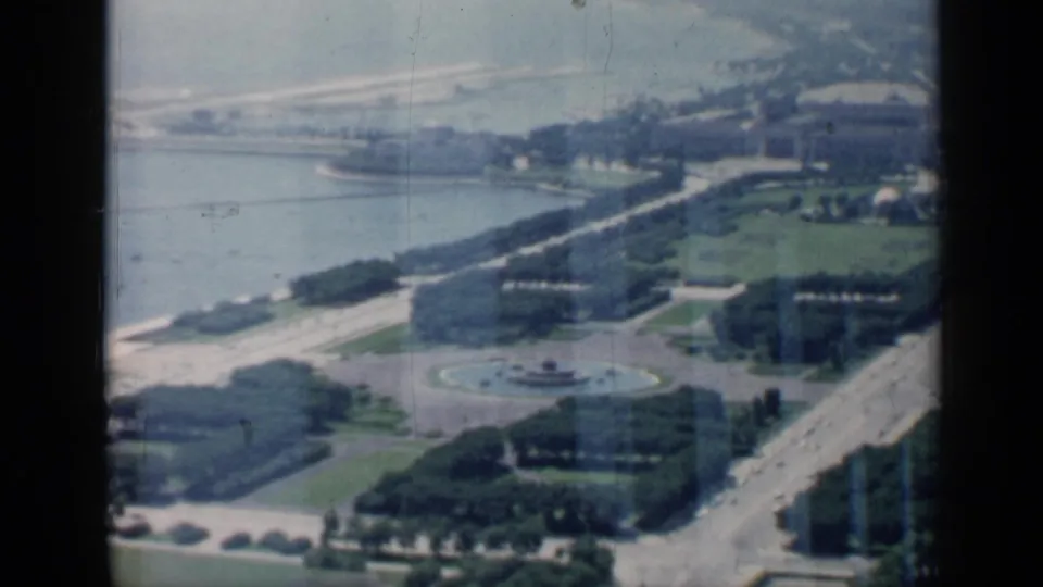 1958 Chicago lakefront park view with roads, green lawns, shoreline, buildings, and a circular fountain visible from above.