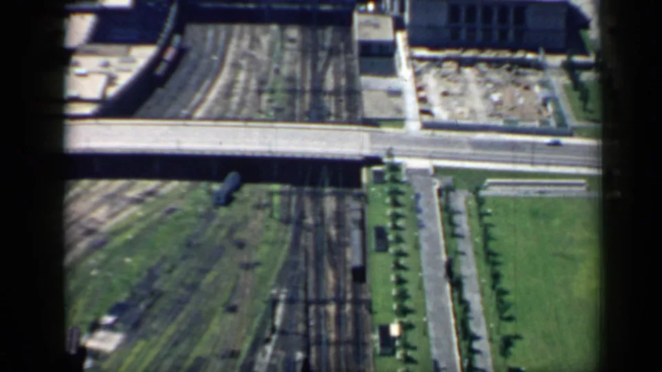 1958 Chicago aerial view centered on rail lines and an overpass, with adjacent roads, lawns, trees, and small trackside structures.